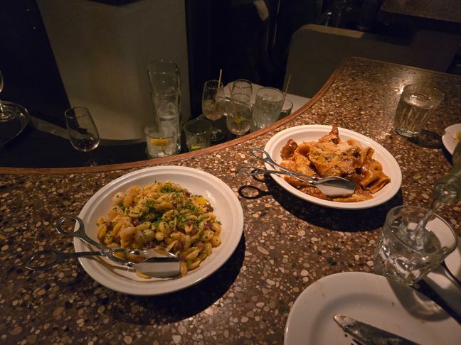 Two plates of pasta,  one is a lamb ragu and the other is prawn with bacon.